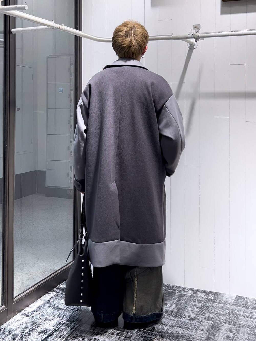 グレー系のトレンチコート、ブルー系のデニムパンツ、レッド系のニット/セーターを着用したメンズの秋コーディネートの3枚目の写真