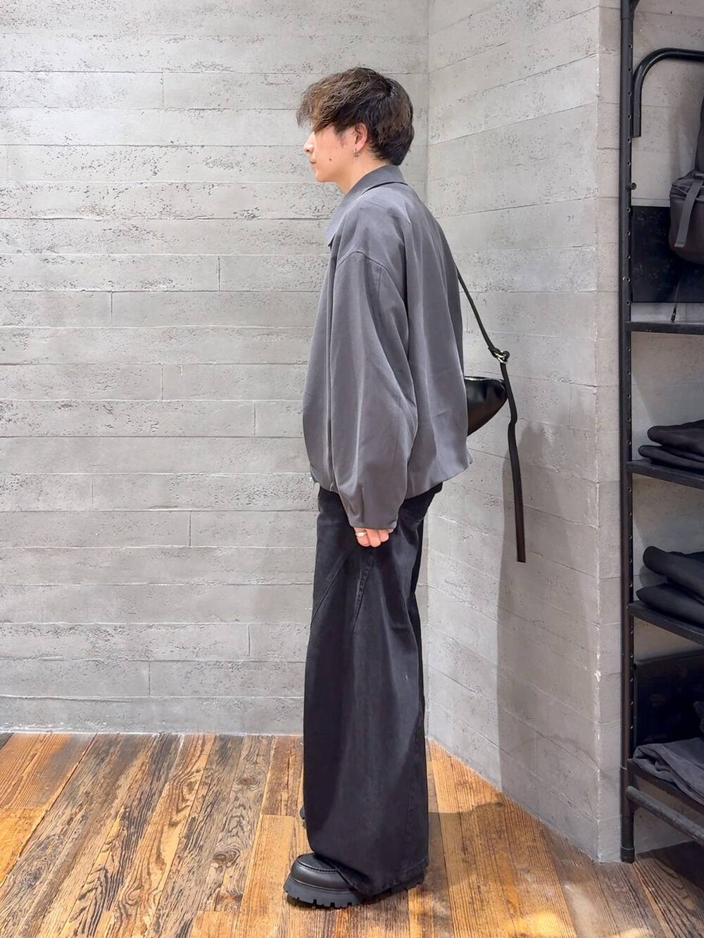 ブラック系のデニムパンツ、ブラック系のドレスシューズ、ブラック系のショルダーバッグを着用したメンズの秋コーディネートの4枚目の写真