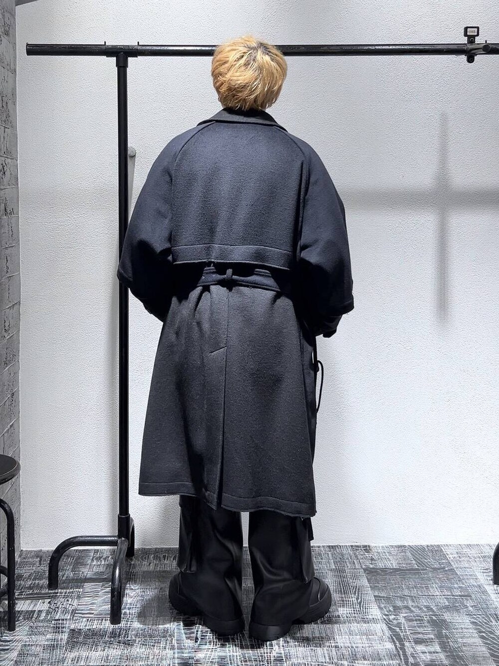 ブラック系のカーゴパンツ、ブラック系のトレンチコート、グレー系のニット/セーターを着用したメンズの冬コーディネートの4枚目の写真