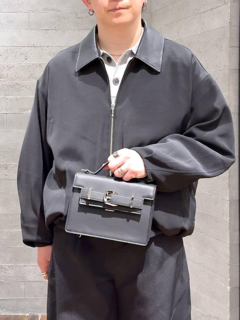 ブラック系のローファー、ブラック系のハンドバッグ、グレー系のポロシャツを着用したメンズの冬コーディネートの4枚目の写真