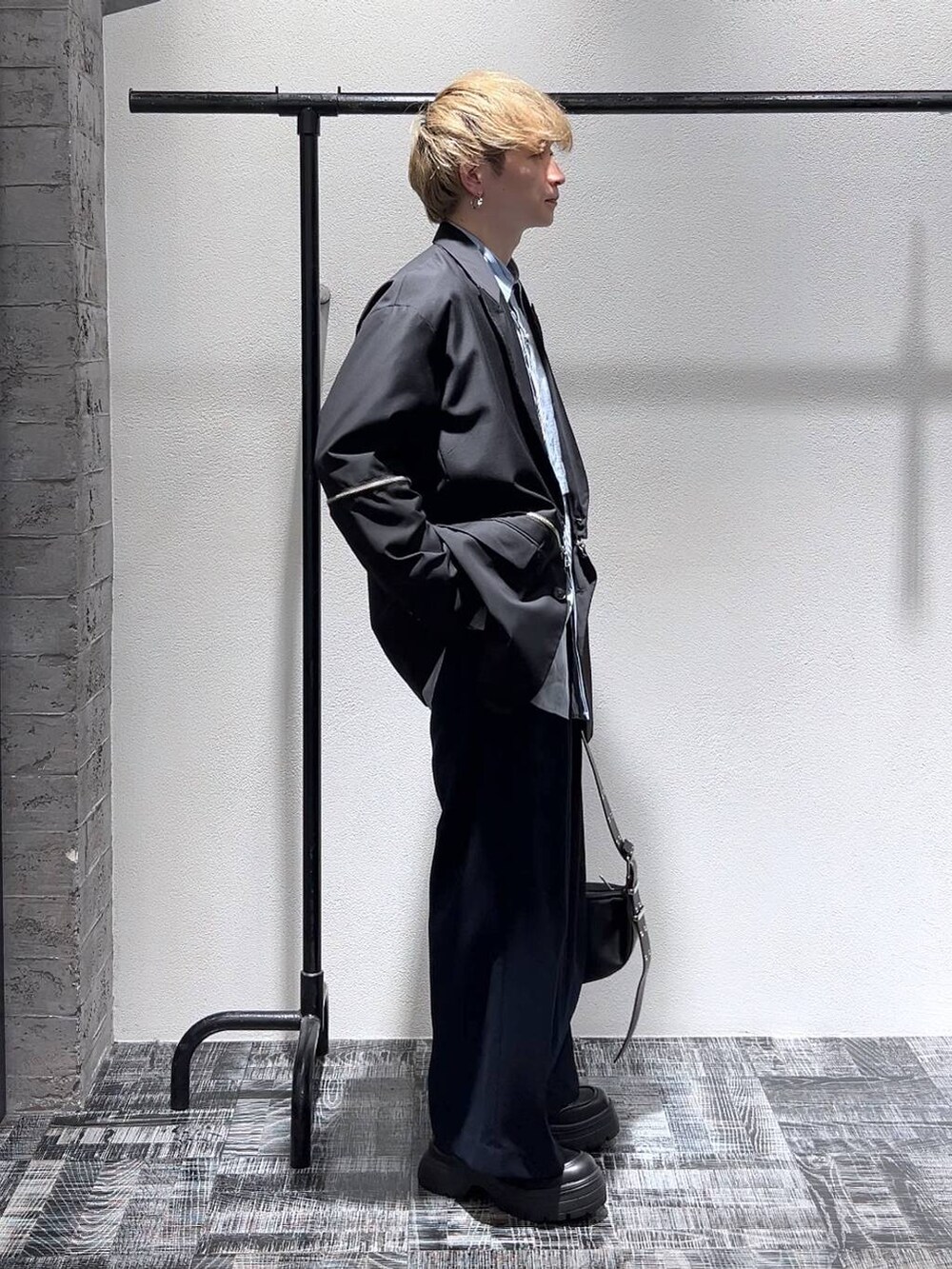 ブラック系のスニーカー、ブルー系のスラックス、ブラック系のショルダーバッグを着用したメンズの春コーディネートの3枚目の写真