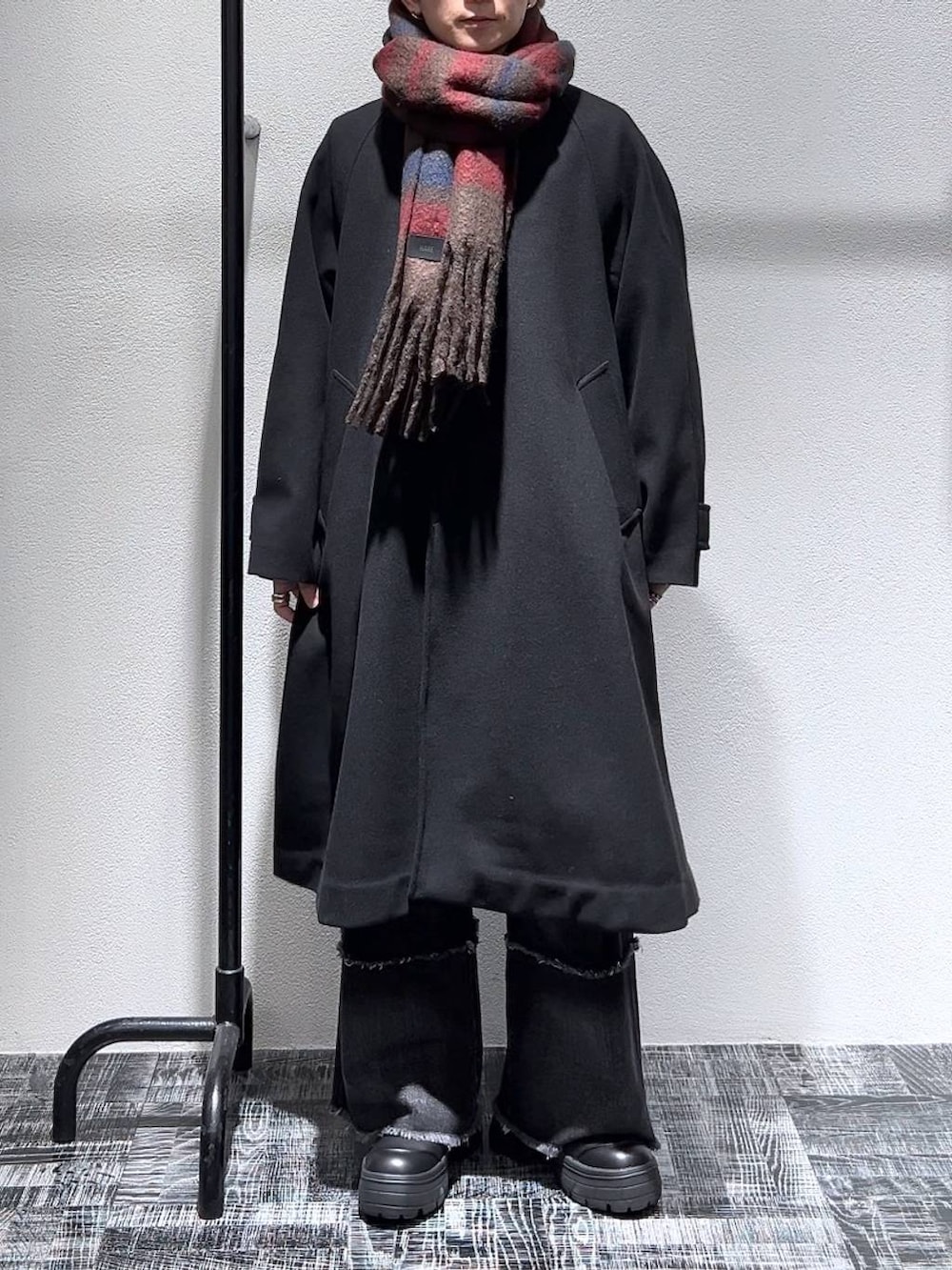 ブラック系のステンカラーコート、ブラック系のデニムパンツ、ブラック系のブーツを着用したメンズの冬コーディネートの2枚目の写真