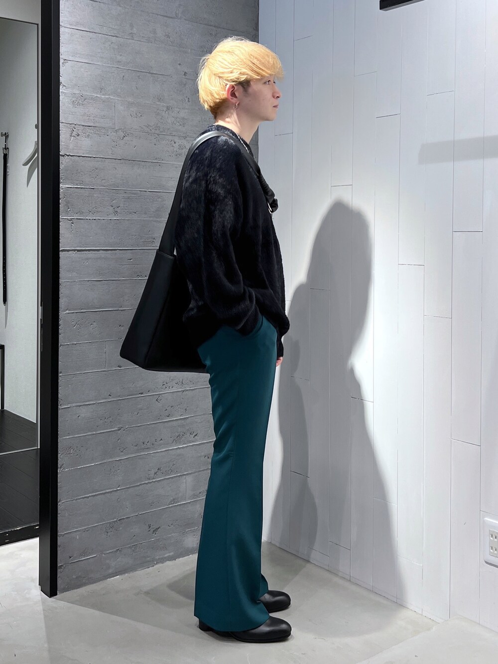 ブラック系のニット/セーター、ブラック系のショルダーバッグ、グリーン系のスラックスを着用したメンズの秋コーディネートの2枚目の写真