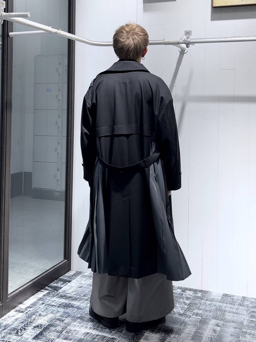 ブラック系のステンカラーコート、ブラック系のニット/セーター、シルバー系のリングを着用したメンズの秋コーディネートの3枚目の写真