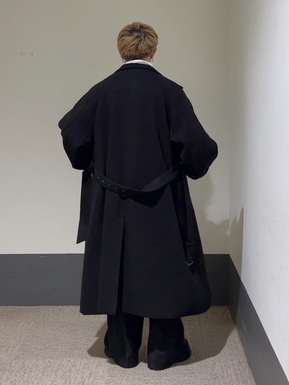 イエロー系のニット/セーター、ホワイト系のシャツ/ブラウス、ブラック系のステンカラーコートを着用したメンズの秋コーディネートの5枚目の写真