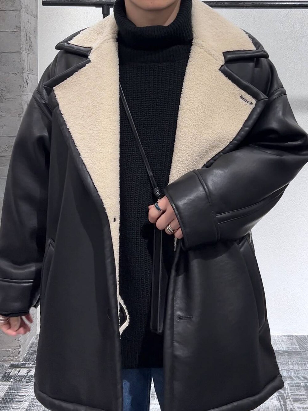 ブラック系のニット/セーター、ブラック系のショルダーバッグ、ブラック系のドレスシューズを着用したメンズの冬コーディネートの5枚目の写真