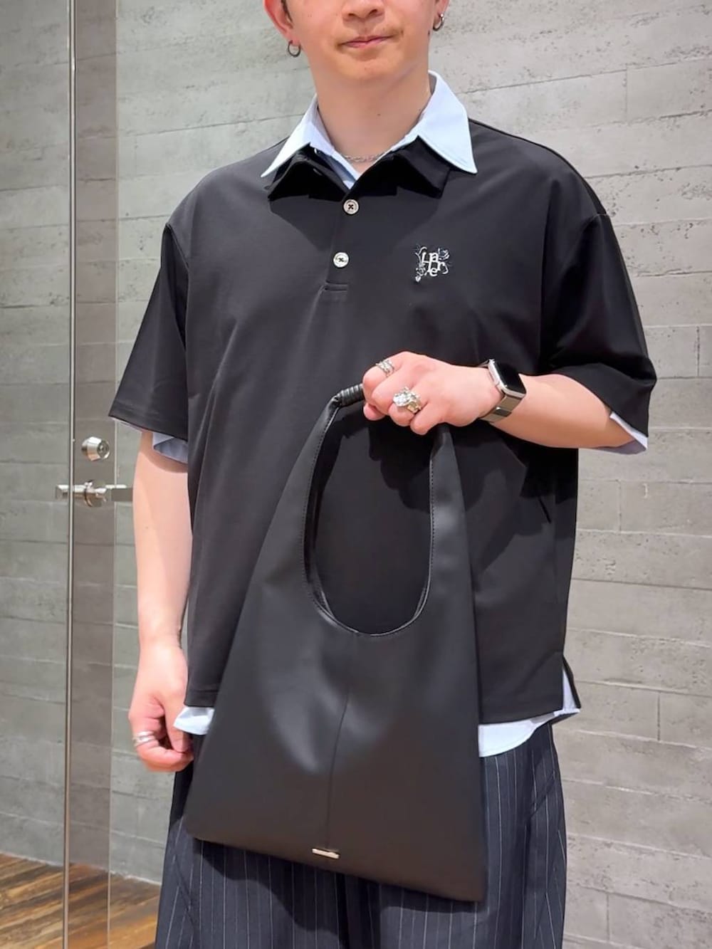 ブラック系のトートバッグ、ブラック系のサンダル、ブルー系のスラックスを着用したメンズの夏コーディネートの5枚目の写真