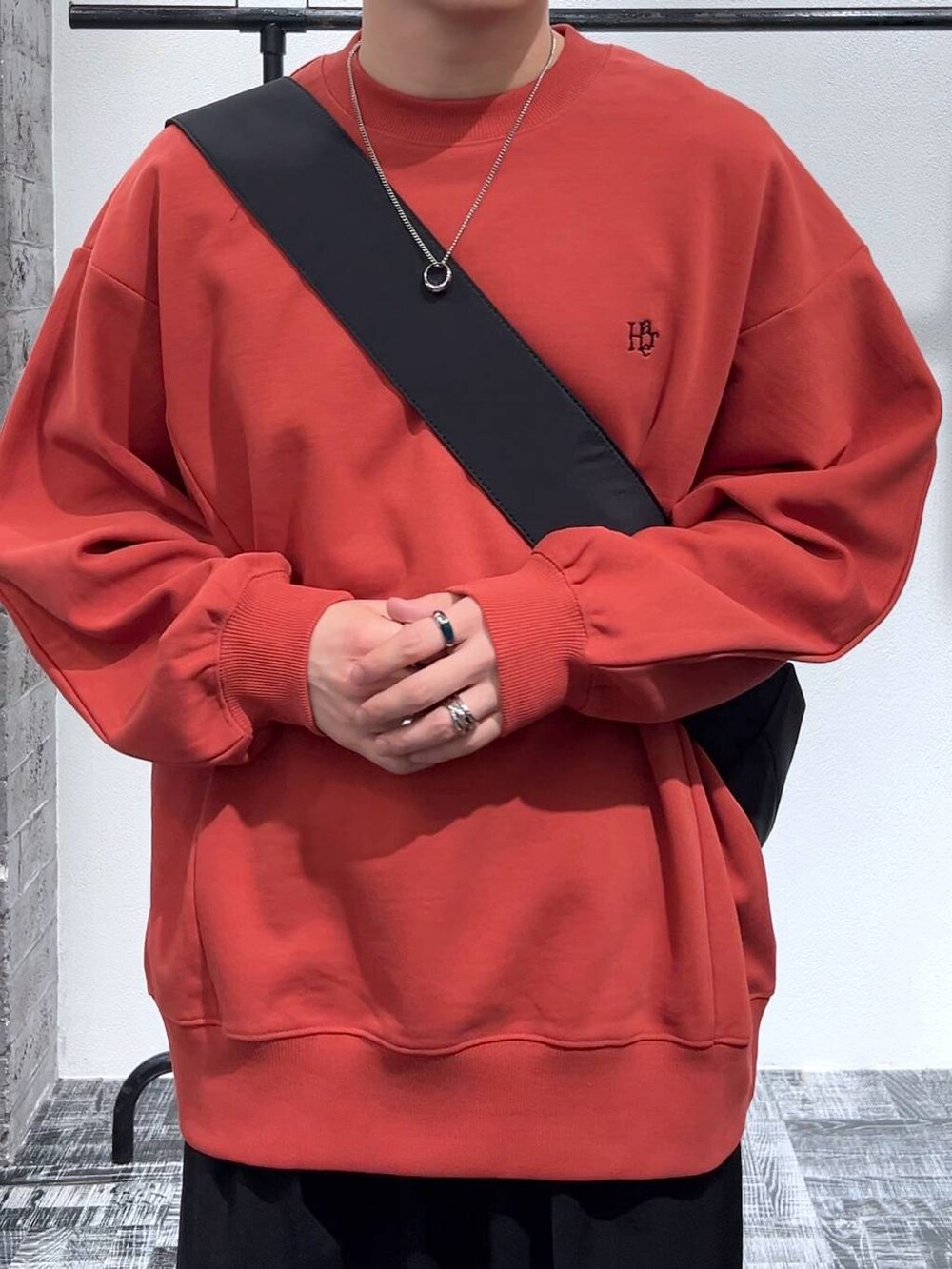 ブラック系のショルダーバッグ、オレンジ系のスウェット、ブラック系のブーツを着用したメンズの冬コーディネートの5枚目の写真