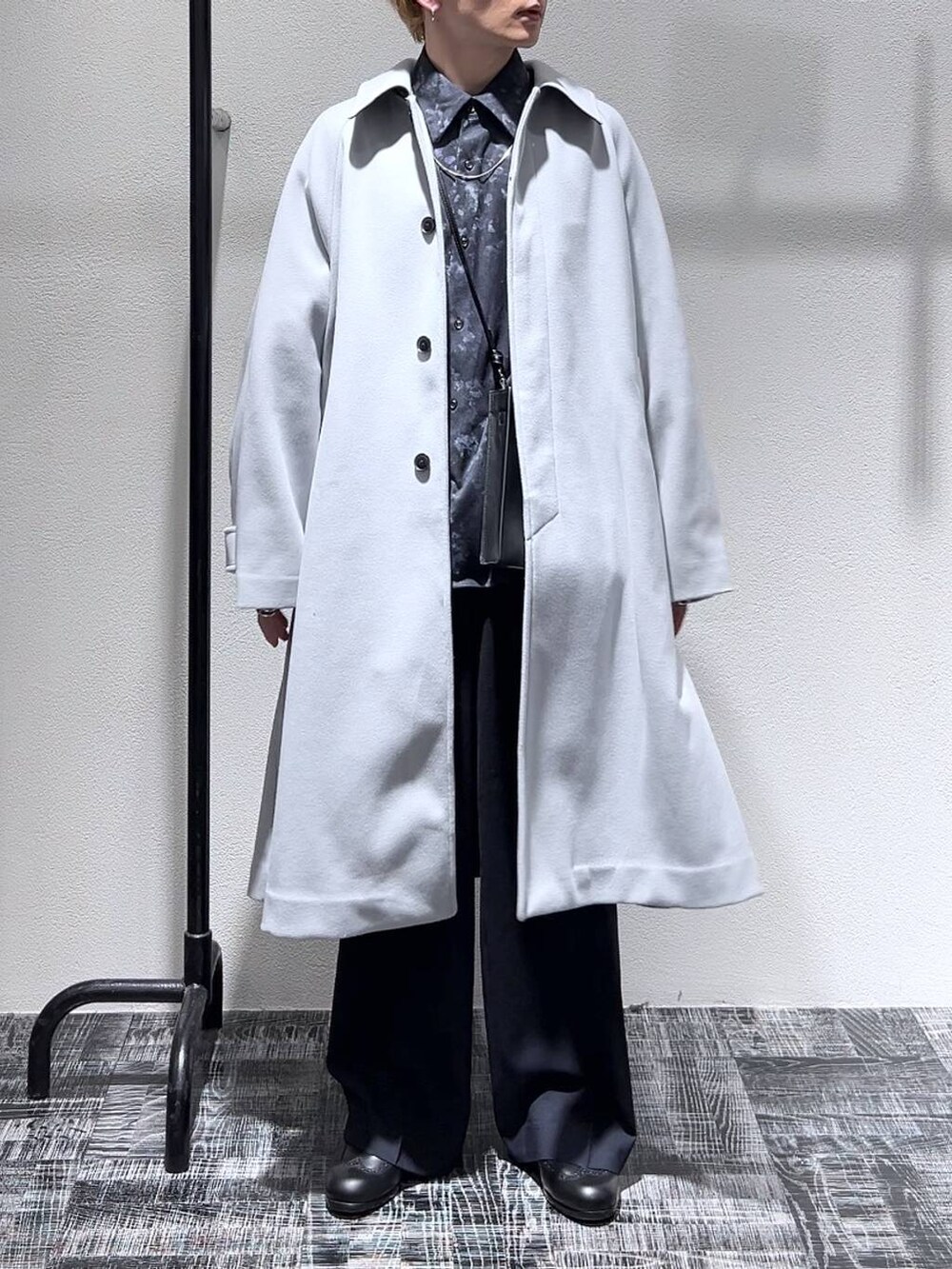 グレー系のステンカラーコート、ブラック系のショルダーバッグ、ブラック系のドレスシューズを着用したメンズの冬コーディネートの2枚目の写真