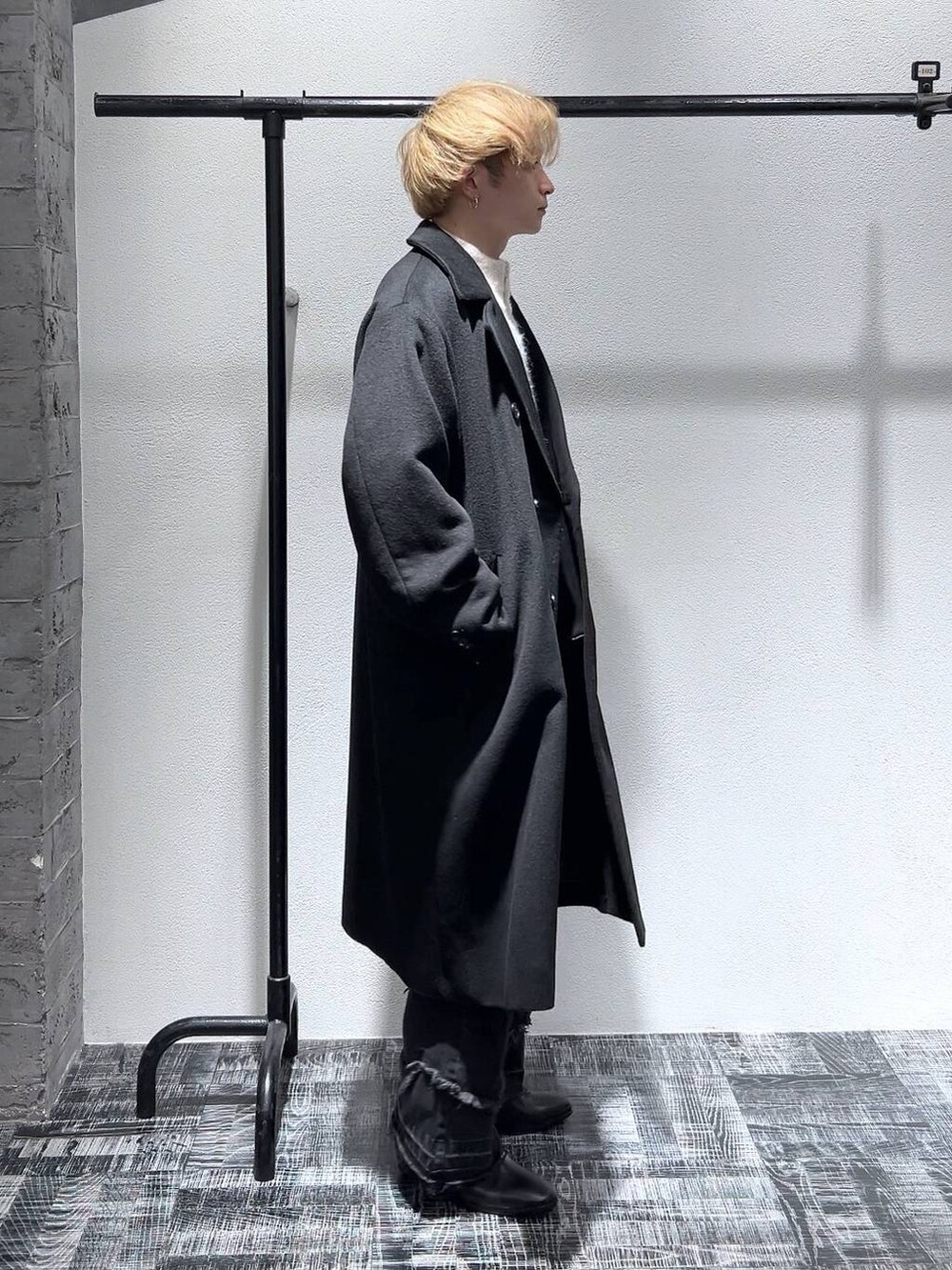 ブラック系のドレスシューズ、ブラック系のステンカラーコート、ブラック系のショルダーバッグを着用したメンズの冬コーディネートの4枚目の写真