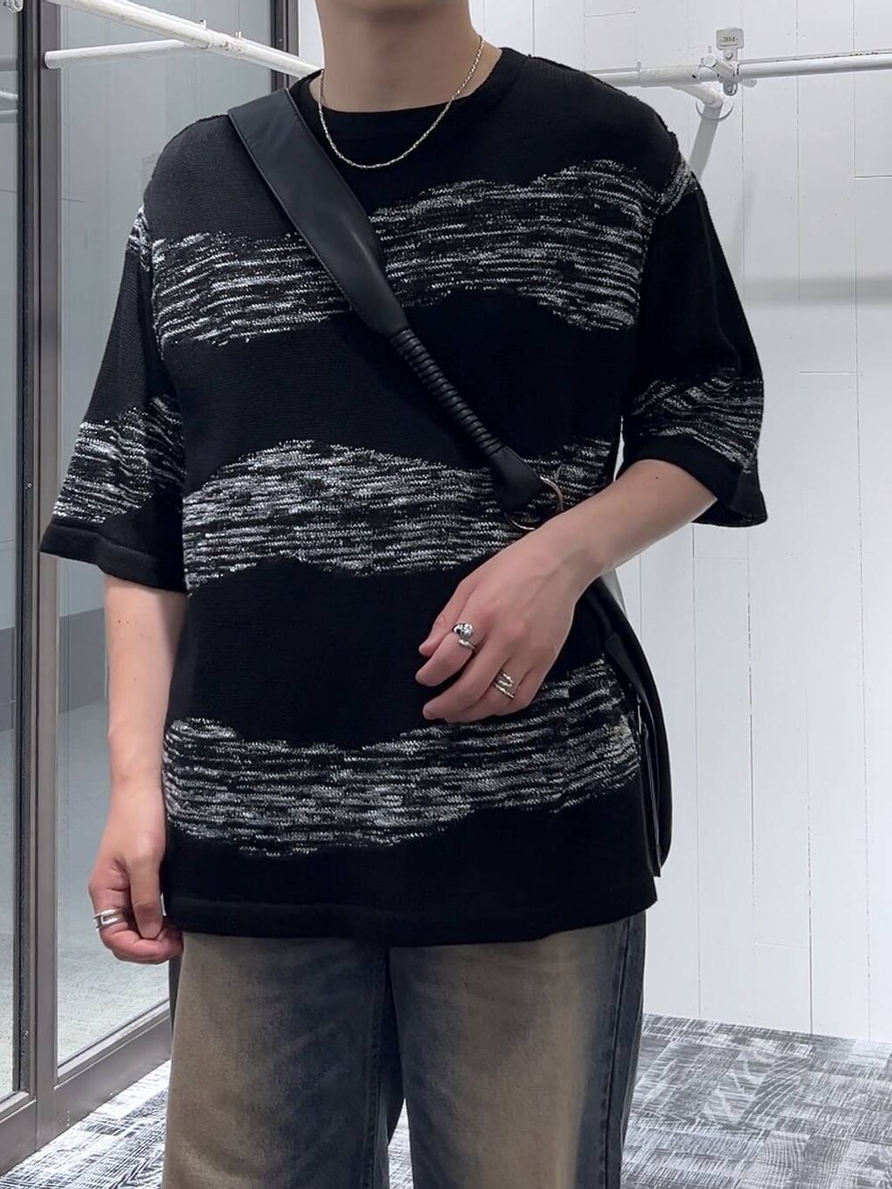 ブルー系のデニムパンツ、ブラック系のショルダーバッグ、ブラック系のニット/セーターを着用したメンズの夏コーディネートの6枚目の写真