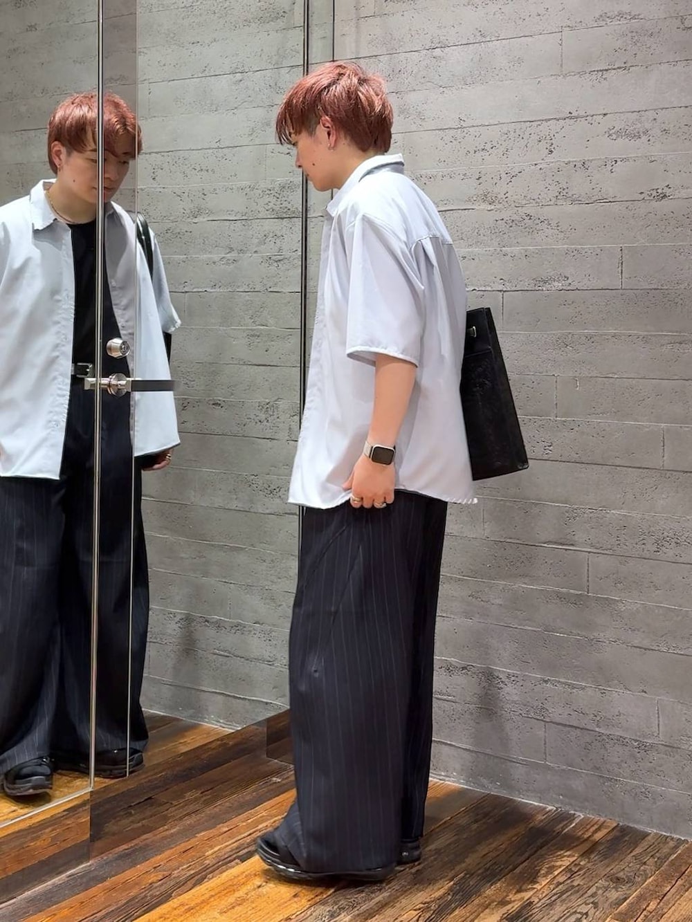 ブラック系のサンダル、ブラック系のTシャツ/カットソー、ブルー系のスラックスを着用したメンズの夏コーディネートの4枚目の写真