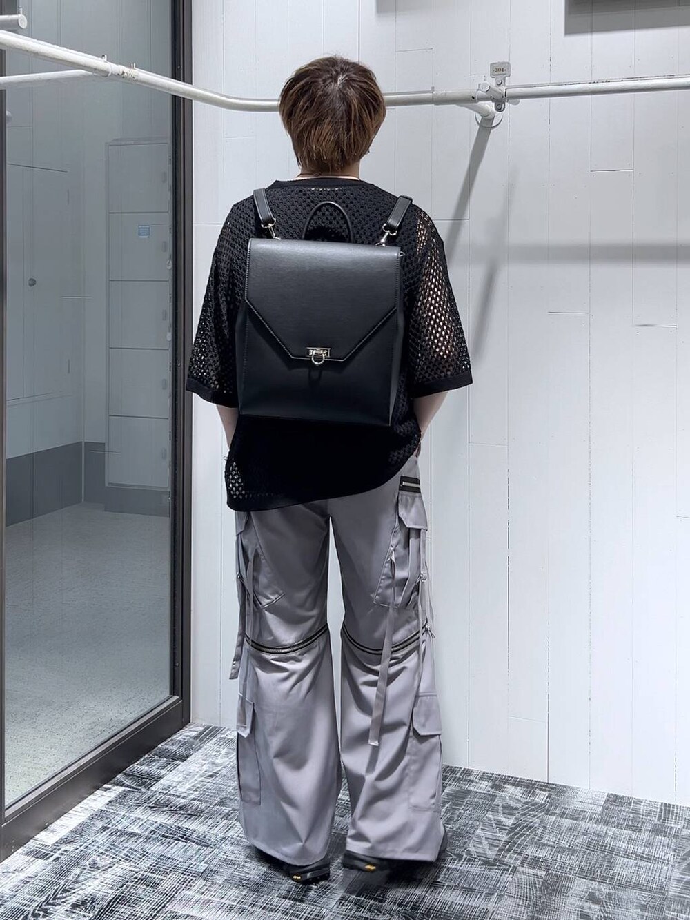 ブラック系のニット/セーター、グレー系のカーゴパンツ、ブラック系のTシャツ/カットソーを着用したメンズの春コーディネートの3枚目の写真