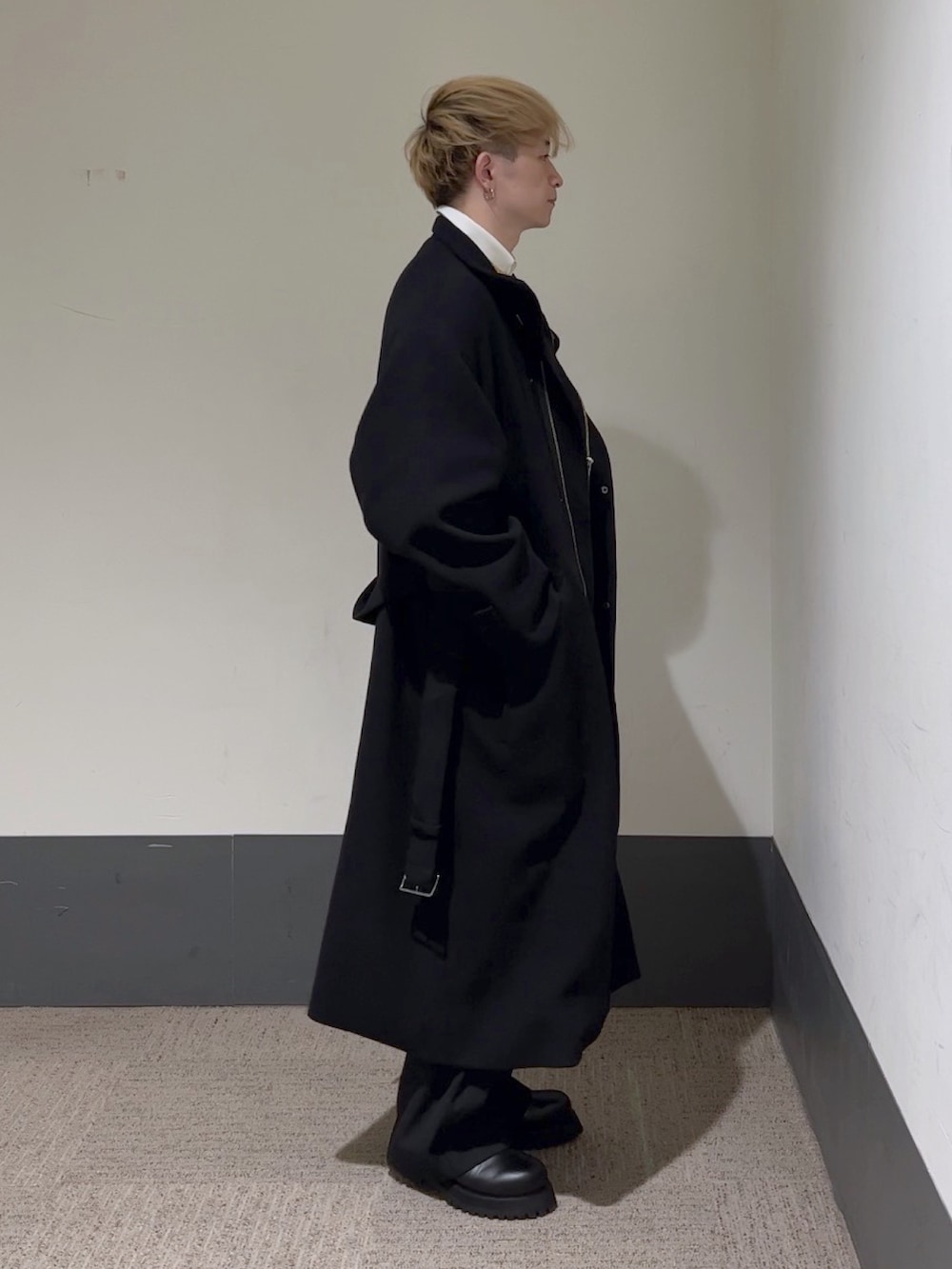 イエロー系のニット/セーター、ホワイト系のシャツ/ブラウス、ブラック系のステンカラーコートを着用したメンズの秋コーディネートの4枚目の写真