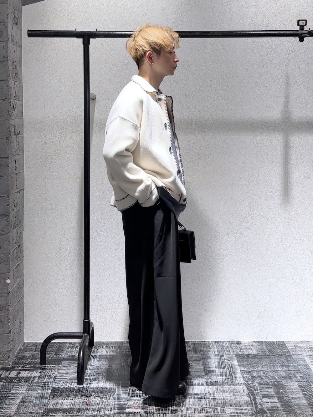 グレー系のスウェット、ホワイト系のニット/セーター、ブラック系のパンツを着用したメンズの秋コーディネートの2枚目の写真