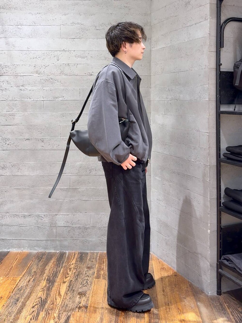 ブラック系のデニムパンツ、ブラック系のドレスシューズ、ブラック系のショルダーバッグを着用したメンズの秋コーディネートの2枚目の写真