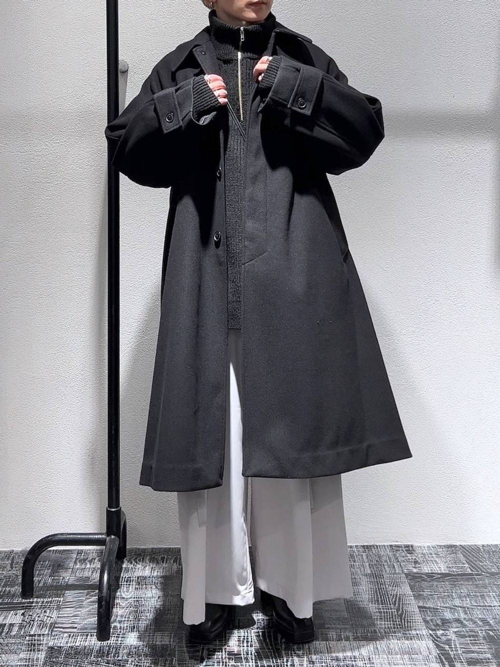 ブラック系のブーツ、ブラック系のステンカラーコート、ブラック系のショルダーバッグを着用したメンズの冬コーディネートの2枚目の写真