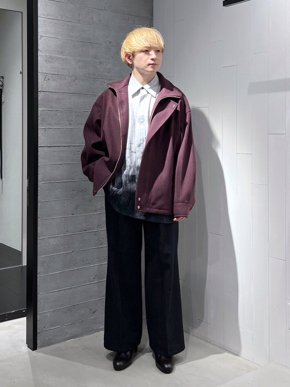 レッド系のブルゾン、ブルー系のデニムパンツ、ブラック系のブーツを着用したメンズの秋コーディネートの2枚目の写真