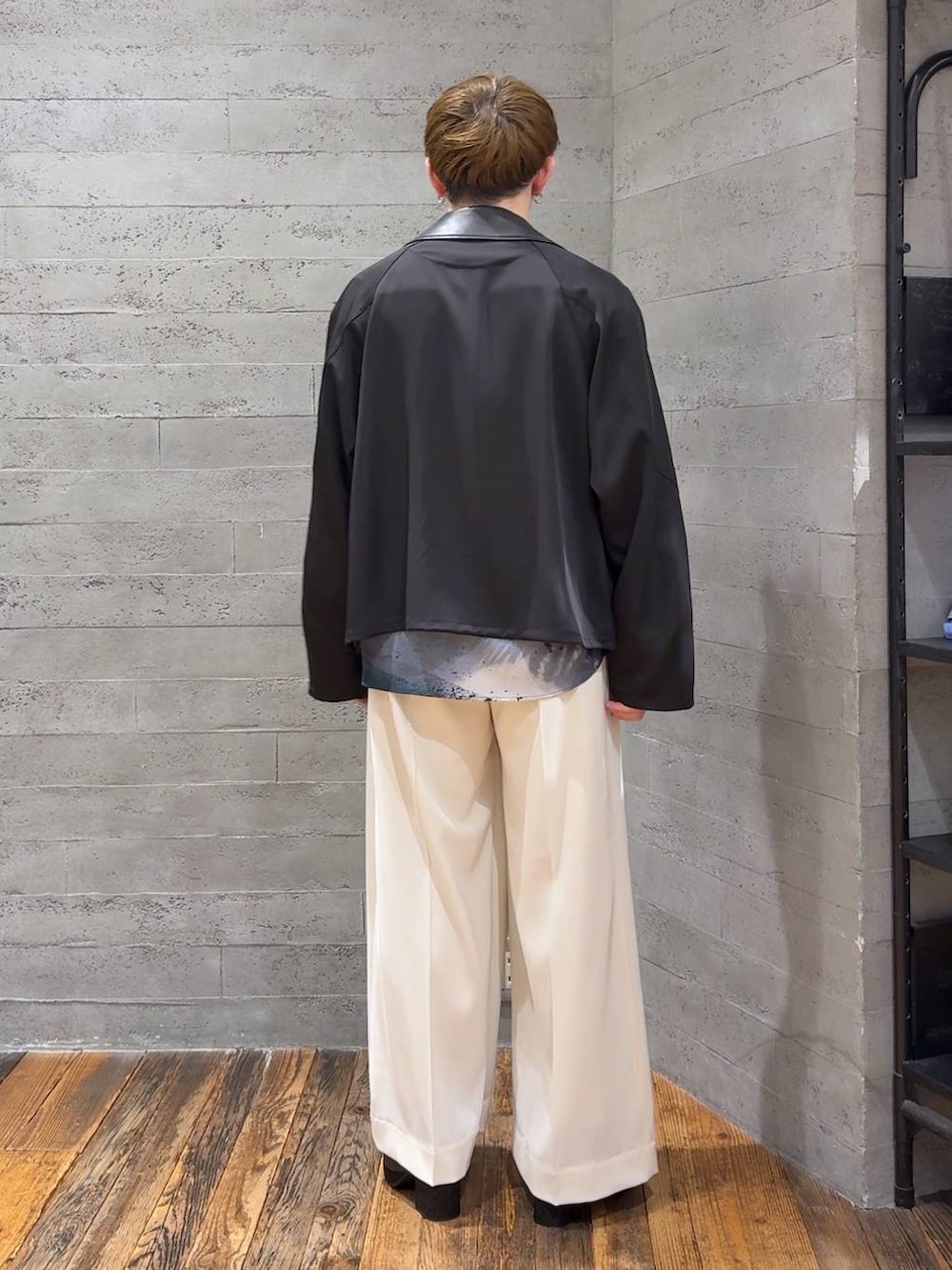 ブラック系のブーツ、ホワイト系のスラックス、ブラック系のブルゾンを着用したメンズの春コーディネートの3枚目の写真