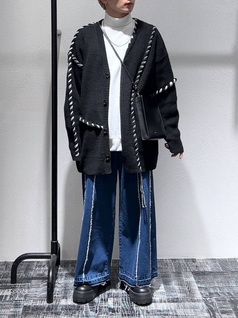 ブルー系のデニムパンツ、ブラック系のショルダーバッグ、ホワイト系のスウェットを着用したメンズの冬コーディネートの2枚目の写真