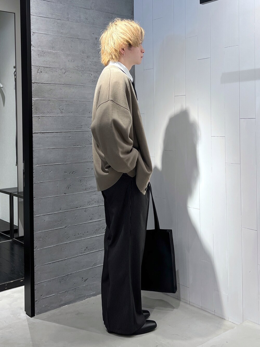ブラック系のスラックス、ブラウン系のカーディガン/ボレロ、ホワイト系のシャツ/ブラウスを着用したメンズの冬コーディネートの2枚目の写真