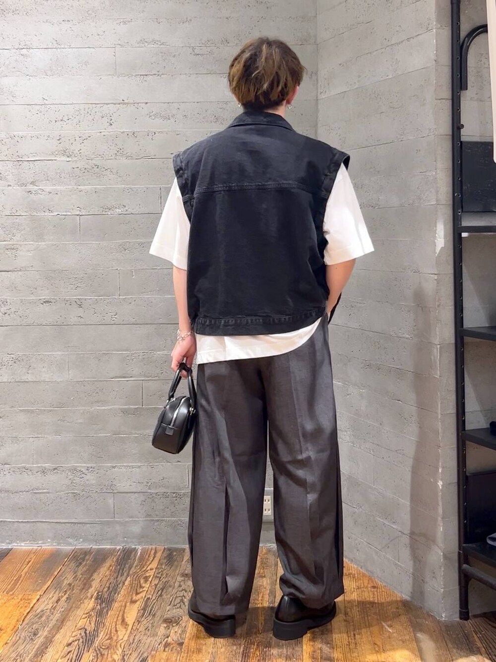 ブラック系のスラックス、ブラック系のローファー、ホワイト系のTシャツ/カットソーを着用したメンズの夏コーディネートの3枚目の写真