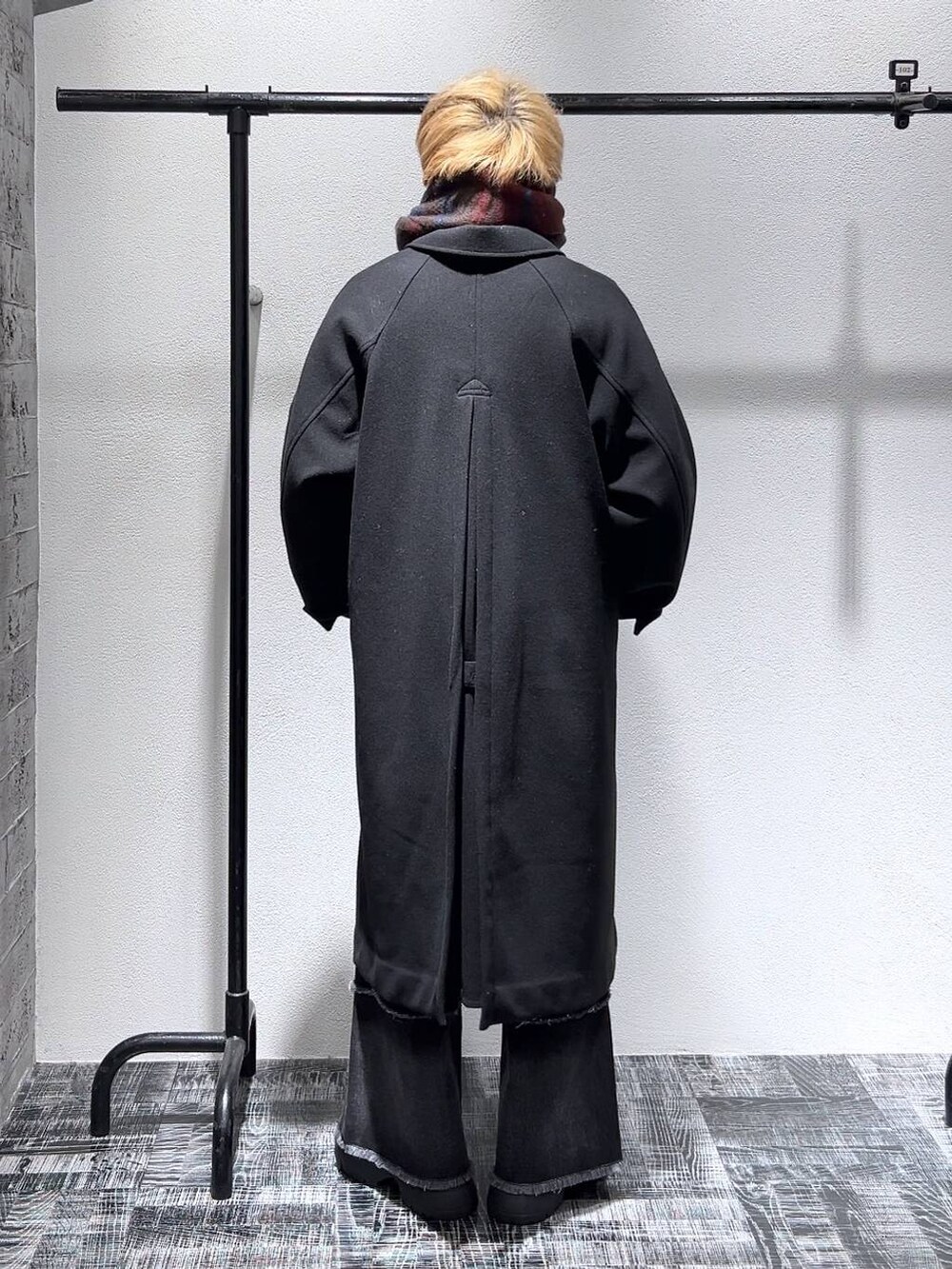 ブラック系のステンカラーコート、ブラック系のデニムパンツ、ブラック系のブーツを着用したメンズの冬コーディネートの4枚目の写真