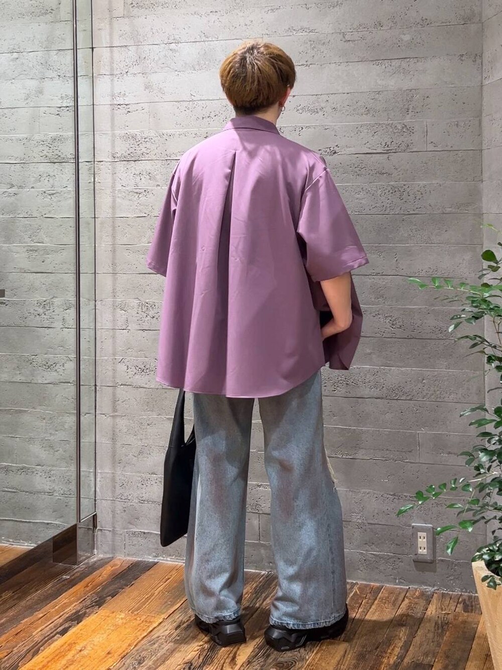 ブラック系のトートバッグ、ブルー系のデニムパンツ、ブラック系のサンダルを着用したメンズの夏コーディネートの3枚目の写真