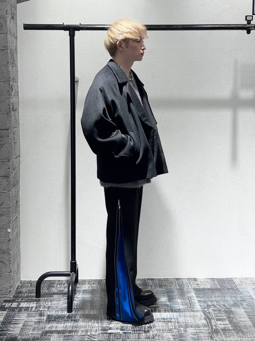 ブラック系のブルゾン、ブラック系のブーツ、ブルー系のスラックスを着用したメンズの秋コーディネートの3枚目の写真