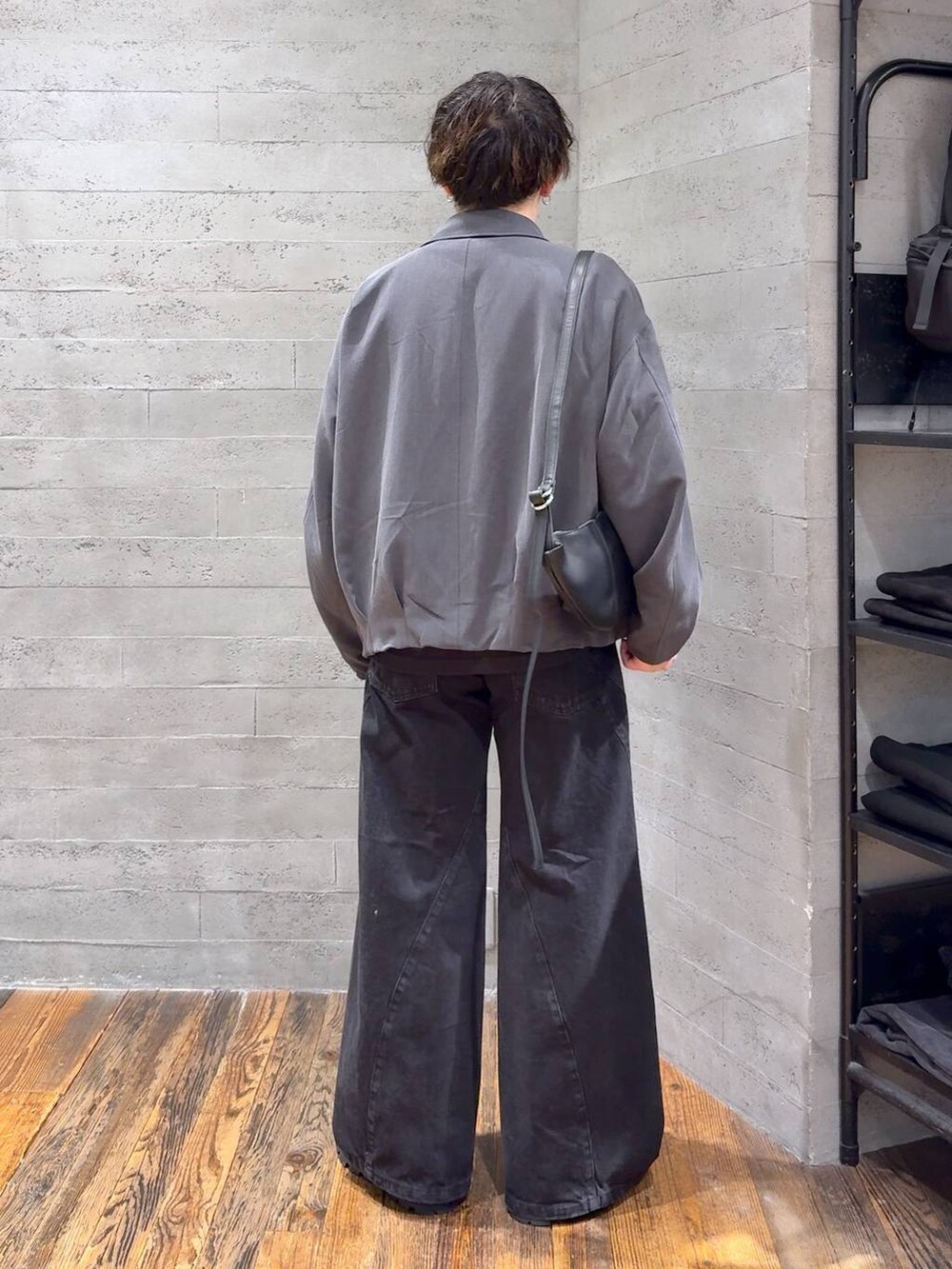 ブラック系のデニムパンツ、ブラック系のドレスシューズ、ブラック系のショルダーバッグを着用したメンズの秋コーディネートの3枚目の写真