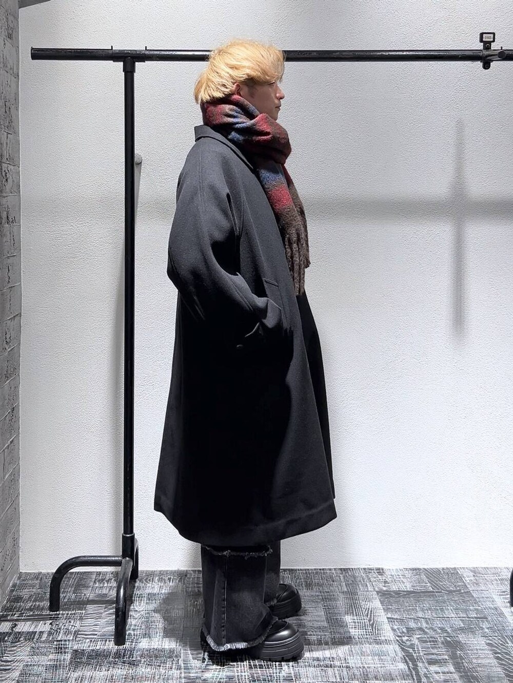 ブラック系のステンカラーコート、ブラック系のデニムパンツ、ブラック系のブーツを着用したメンズの冬コーディネートの3枚目の写真