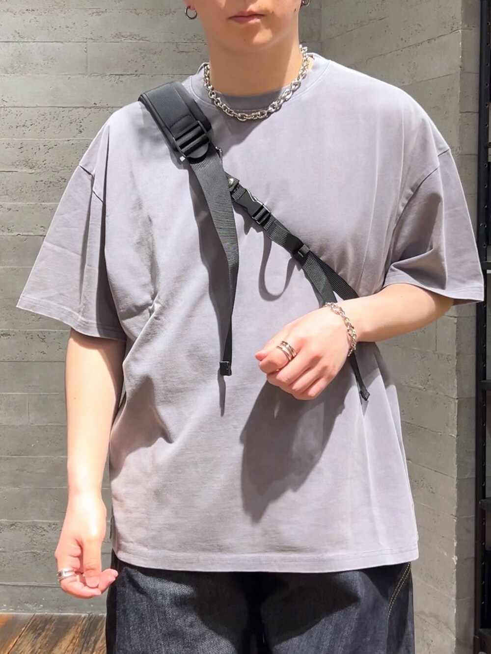ブルー系のデニムパンツ、ブラック系のショルダーバッグ、グレー系のTシャツ/カットソーを着用したメンズの春コーディネートの5枚目の写真