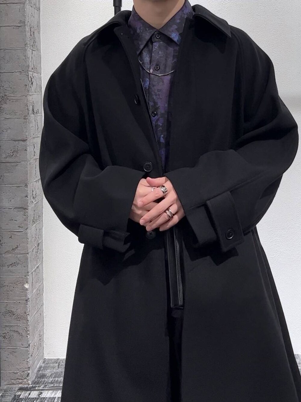 ブラック系のステンカラーコート、ブラック系のショルダーバッグ、ブラック系のブーツを着用したメンズの秋コーディネートの5枚目の写真