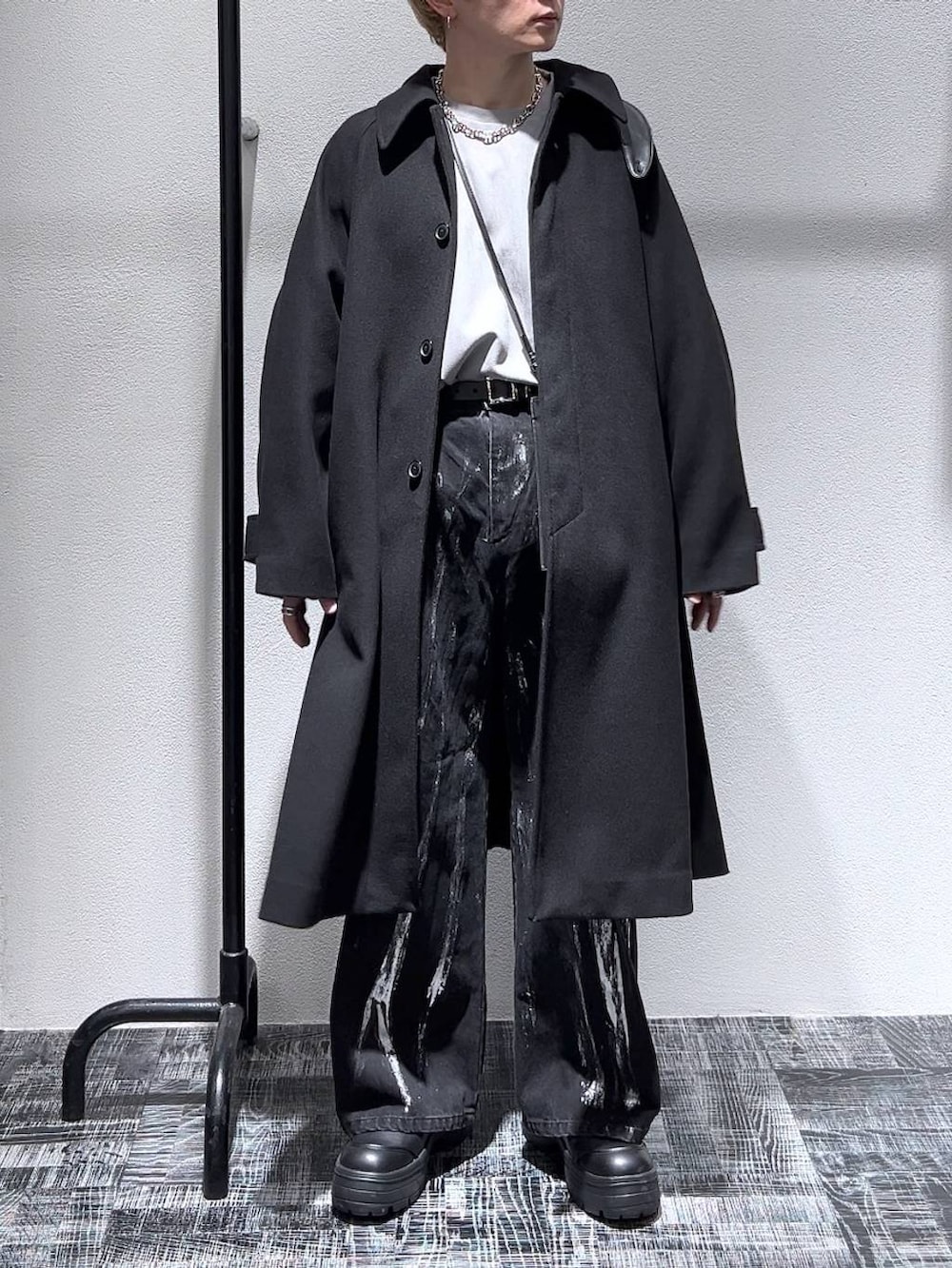 ブラック系のステンカラーコート、グレー系のスウェット、ブラック系のブーツを着用したメンズの冬コーディネートの2枚目の写真