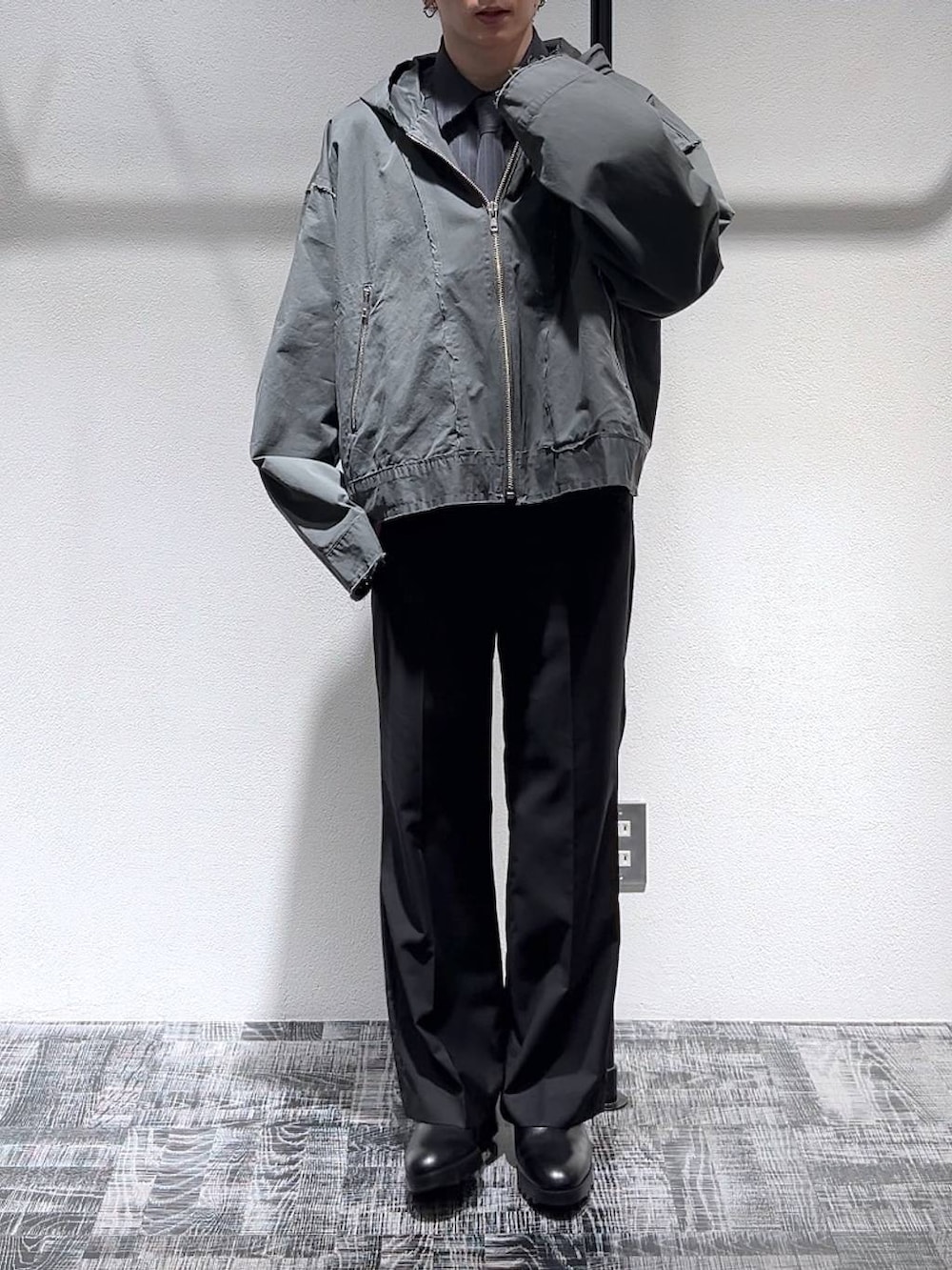 ブラック系のスニーカー、ブラック系のスラックス、グレー系のパーカーを着用したメンズの冬コーディネートの2枚目の写真