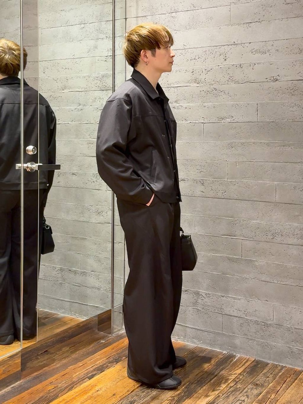 ブラック系のスラックス、ブラック系のブルゾン、ブラック系のショルダーバッグを着用したメンズの春コーディネートの2枚目の写真