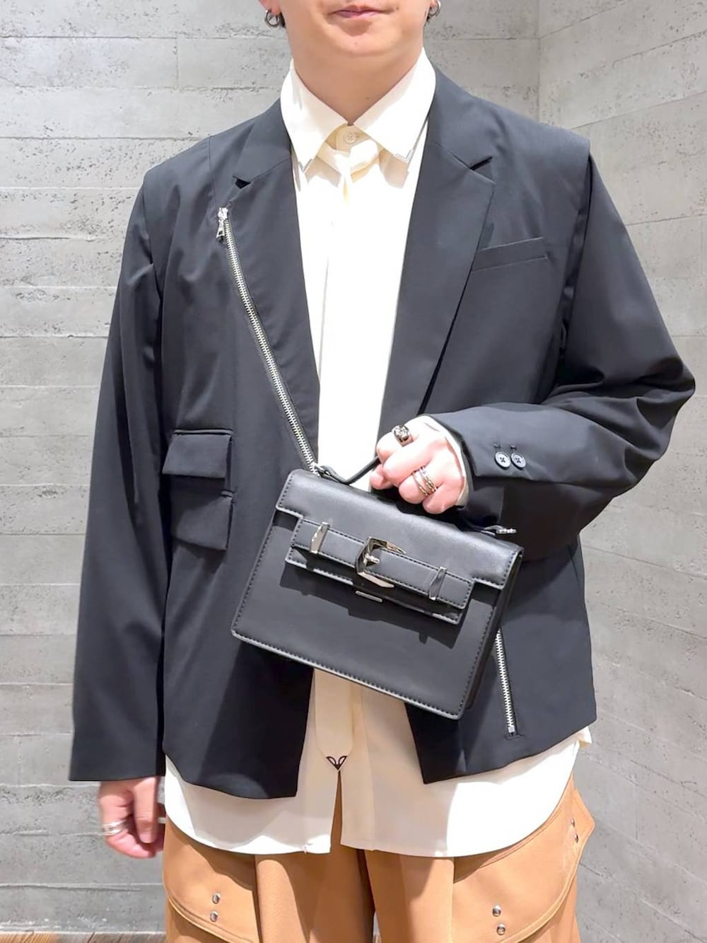 ブラック系のスニーカー、ブラック系のハンドバッグ、ブラック系のテーラードジャケットを着用したメンズの冬コーディネートの5枚目の写真