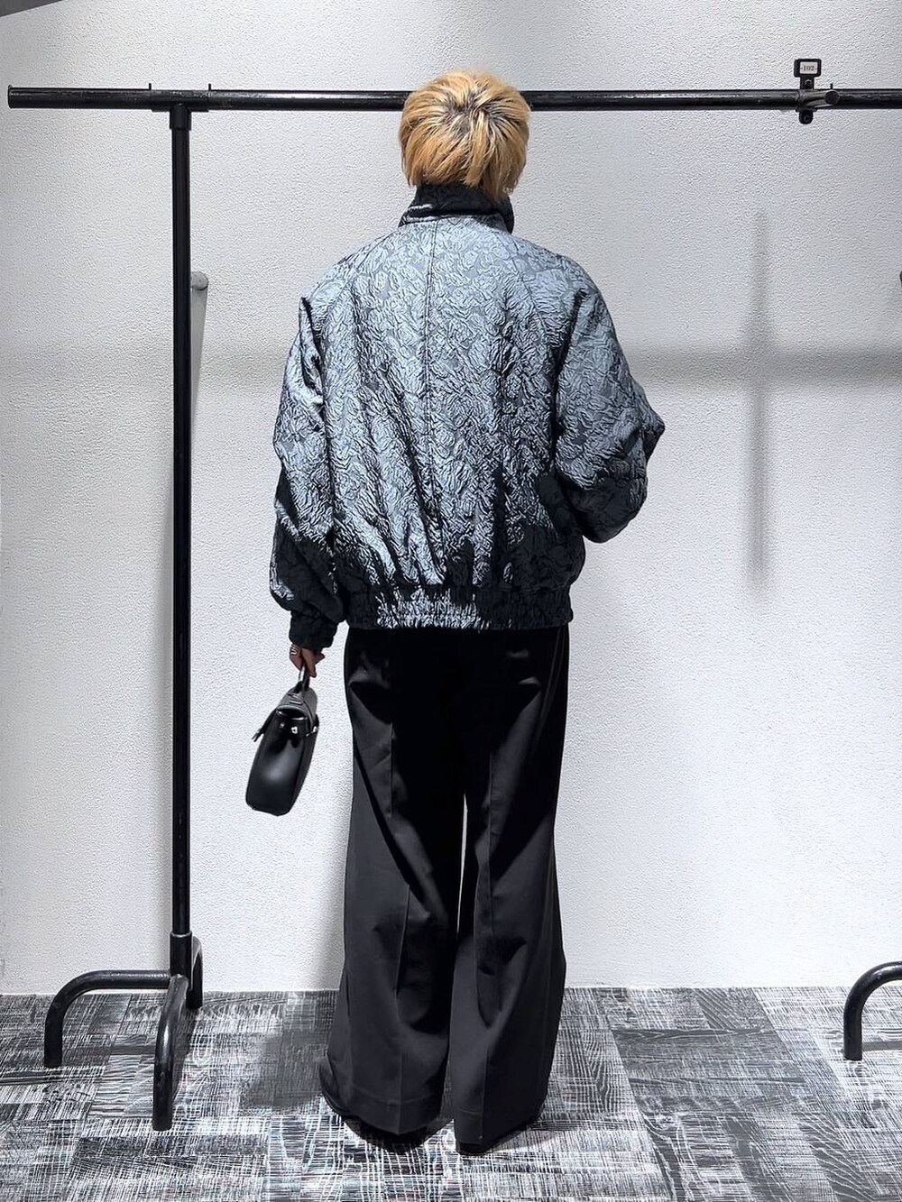 ブラック系のドレスシューズ、ブラック系のショルダーバッグ、ブラック系のスラックスを着用したメンズの冬コーディネートの4枚目の写真