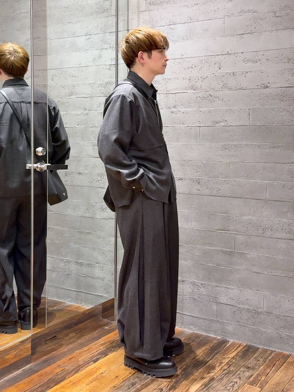 ブラック系のドレスシューズ、ブラック系のスラックス、ブラック系のショルダーバッグを着用したメンズの春コーディネートの2枚目の写真