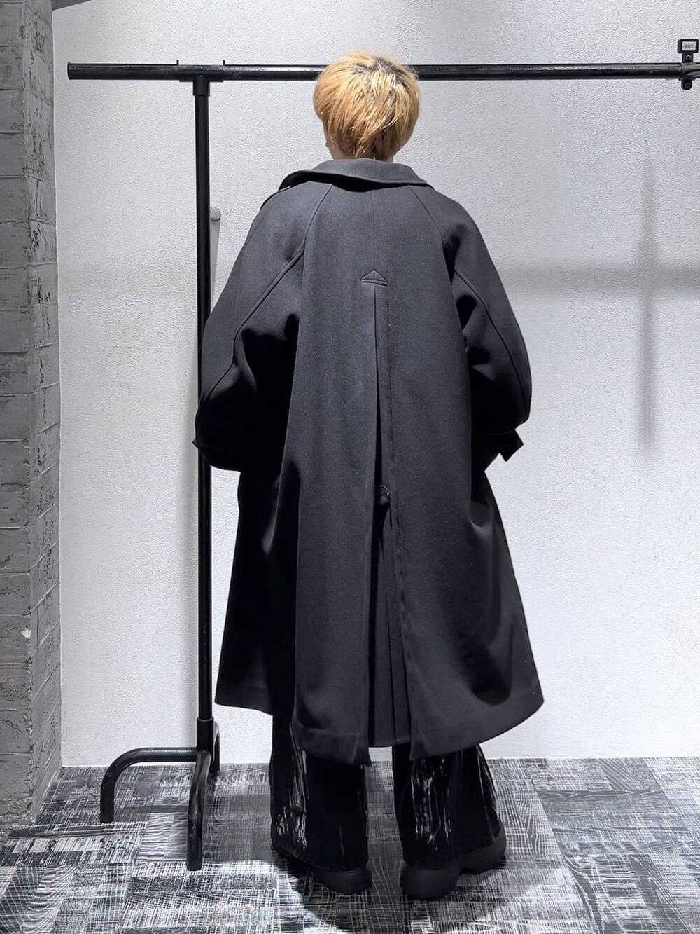 ブラック系のステンカラーコート、グレー系のスウェット、ブラック系のブーツを着用したメンズの冬コーディネートの4枚目の写真