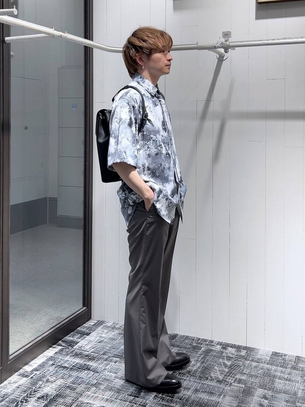 ブラック系のドレスシューズ、ブラック系のショルダーバッグ、グレー系のスラックスを着用したメンズの春コーディネートの3枚目の写真