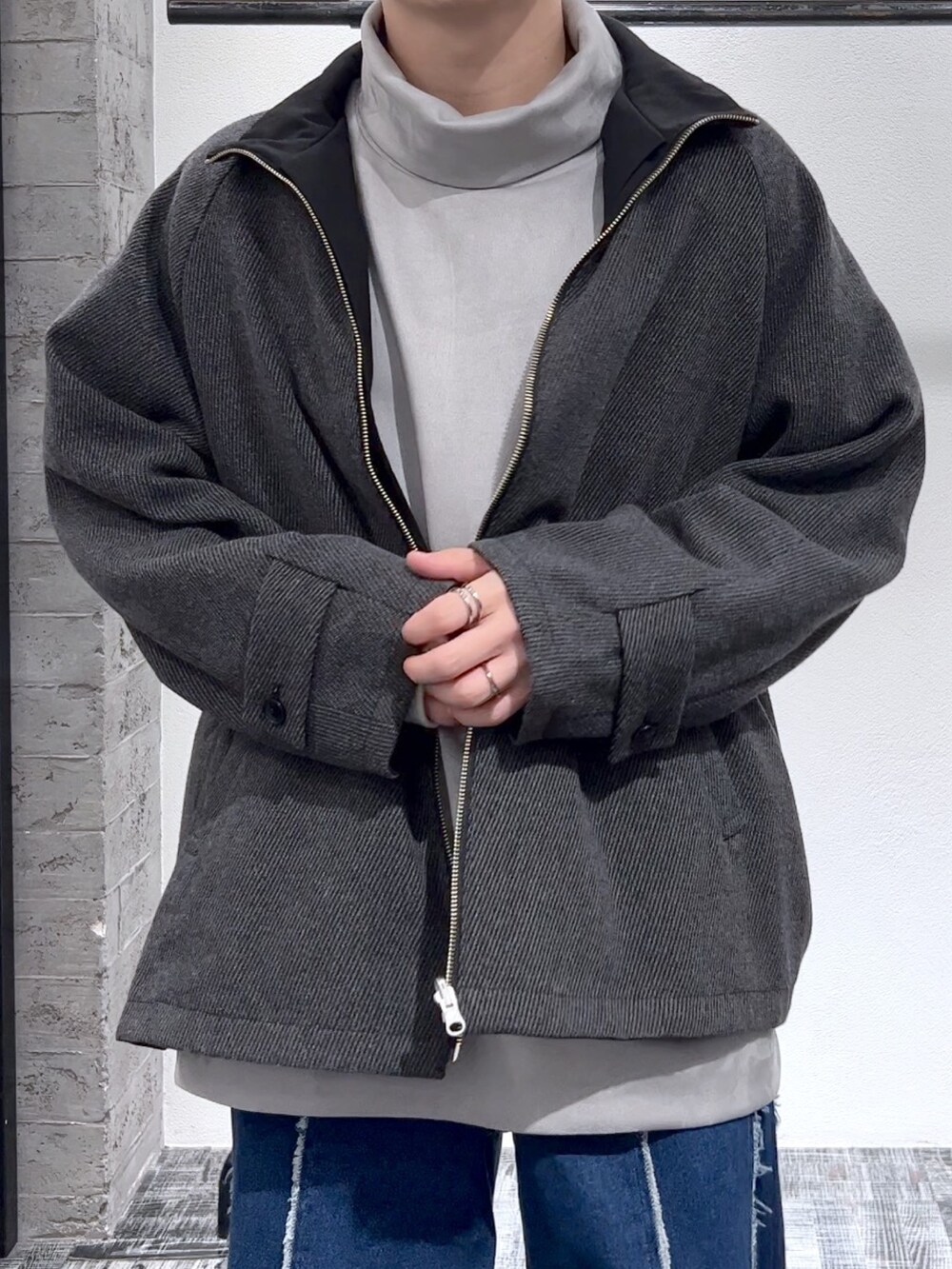 グレー系のスウェット、ブルー系のデニムパンツ、ブラック系のジャケット/アウターを着用したメンズの秋コーディネートの4枚目の写真