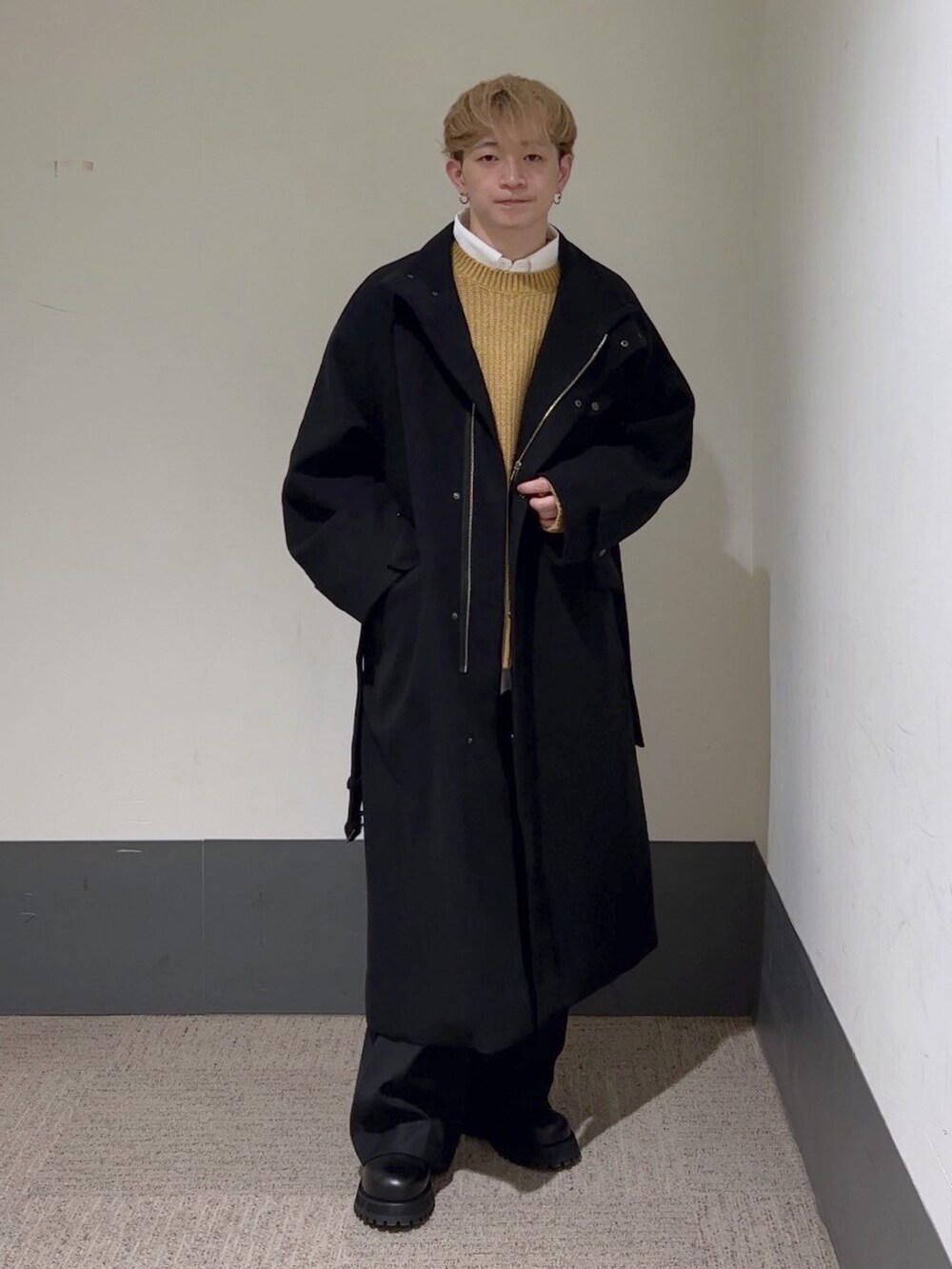 イエロー系のニット/セーター、ホワイト系のシャツ/ブラウス、ブラック系のステンカラーコートを着用したメンズの秋コーディネートの2枚目の写真