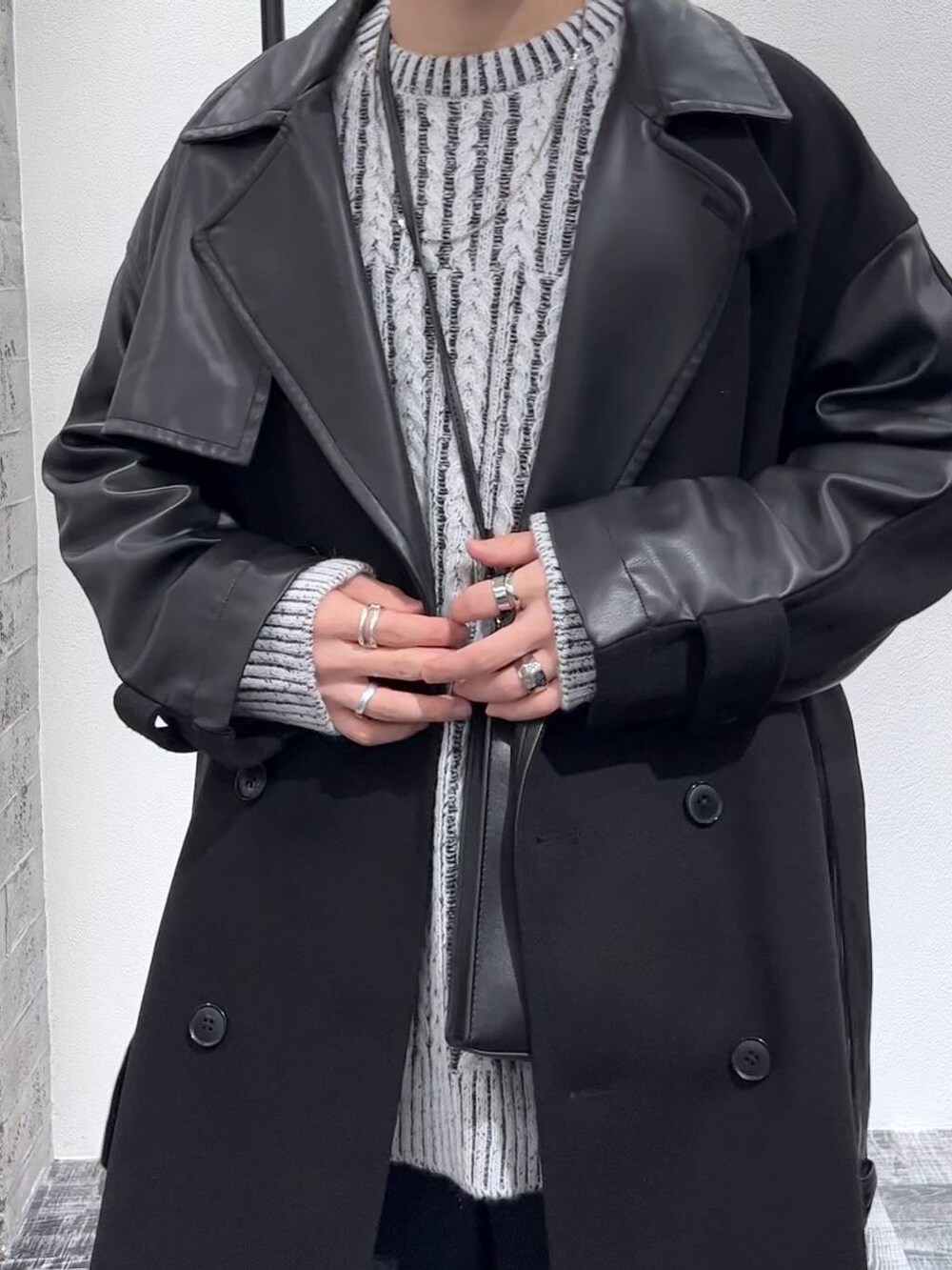 ブルー系のデニムパンツ、ブラック系のトレンチコート、ブラック系のショルダーバッグを着用したメンズの秋コーディネートの5枚目の写真