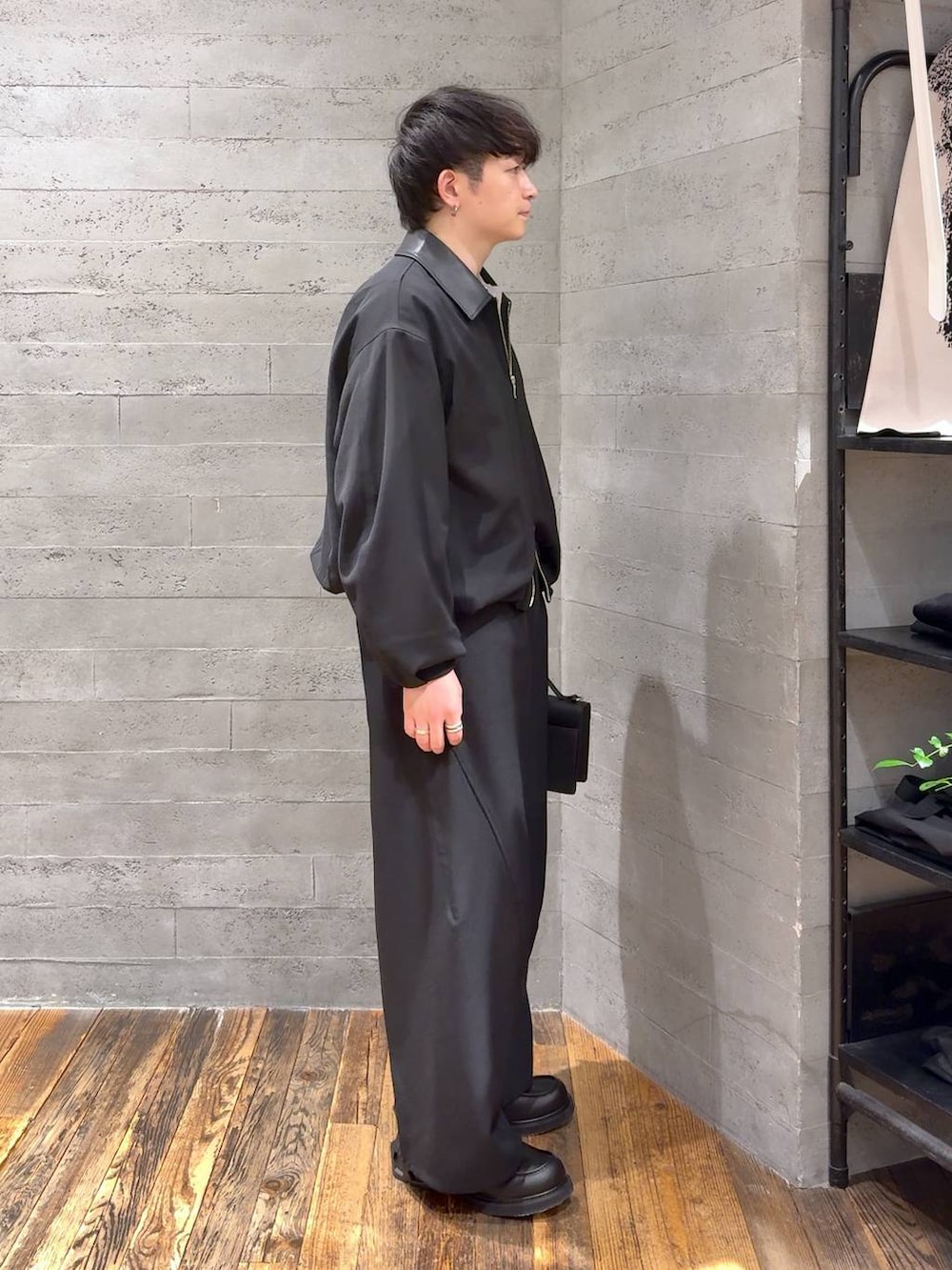 ブラック系のローファー、ブラック系のハンドバッグ、グレー系のポロシャツを着用したメンズの冬コーディネートの2枚目の写真