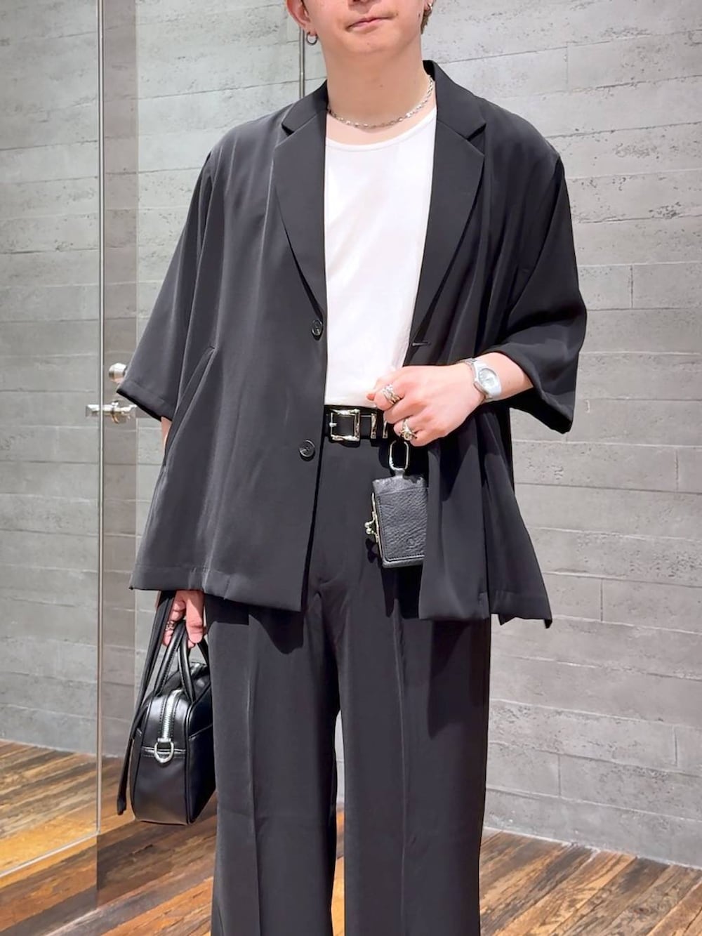 ブラック系のスラックス、ブラック系のサンダル、ホワイト系のTシャツ/カットソーを着用したメンズの夏コーディネートの5枚目の写真