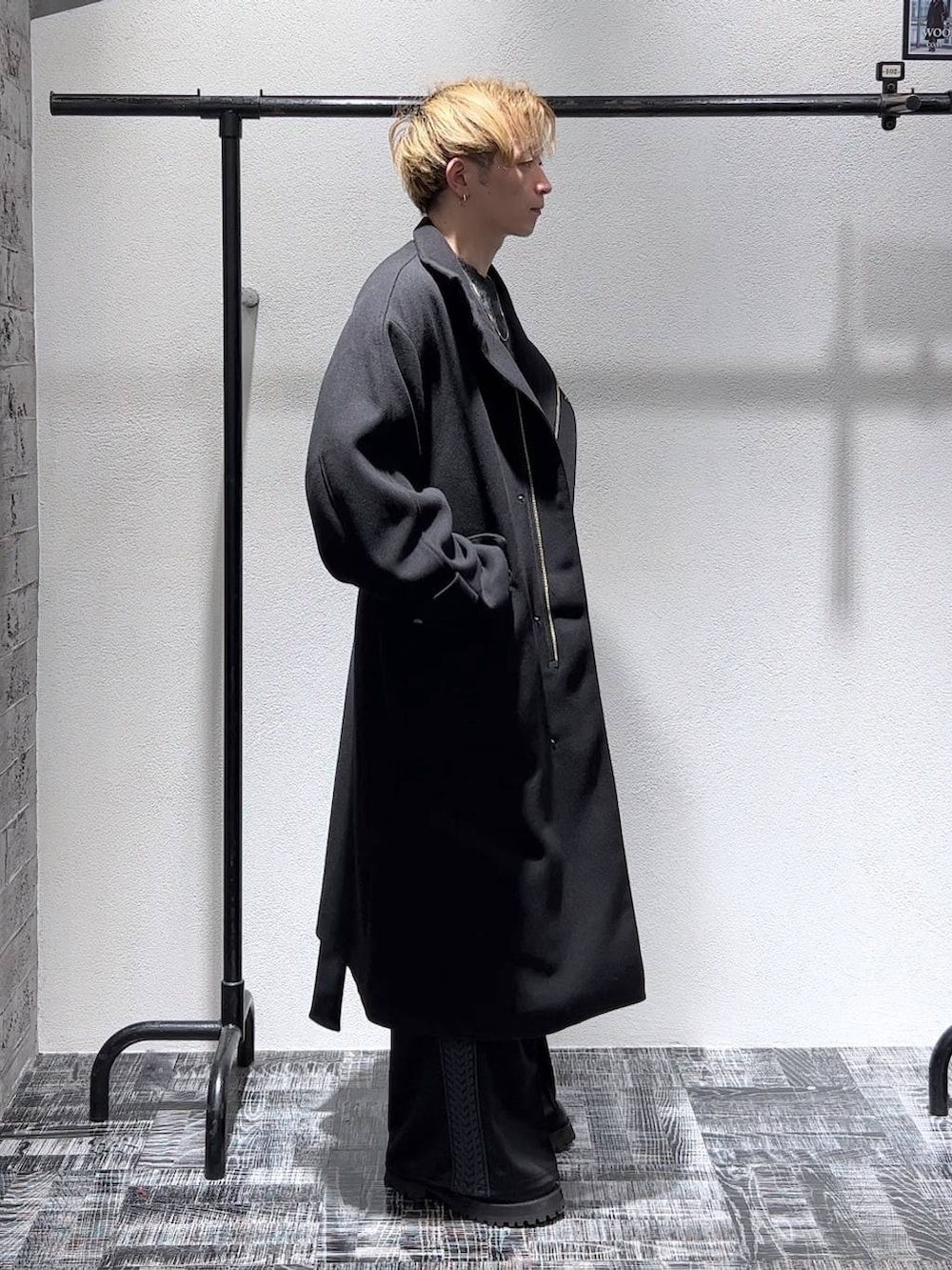 ブラック系のステンカラーコート、ブラック系のブーツ、ブラック系のその他パンツを着用したメンズの秋コーディネートの2枚目の写真