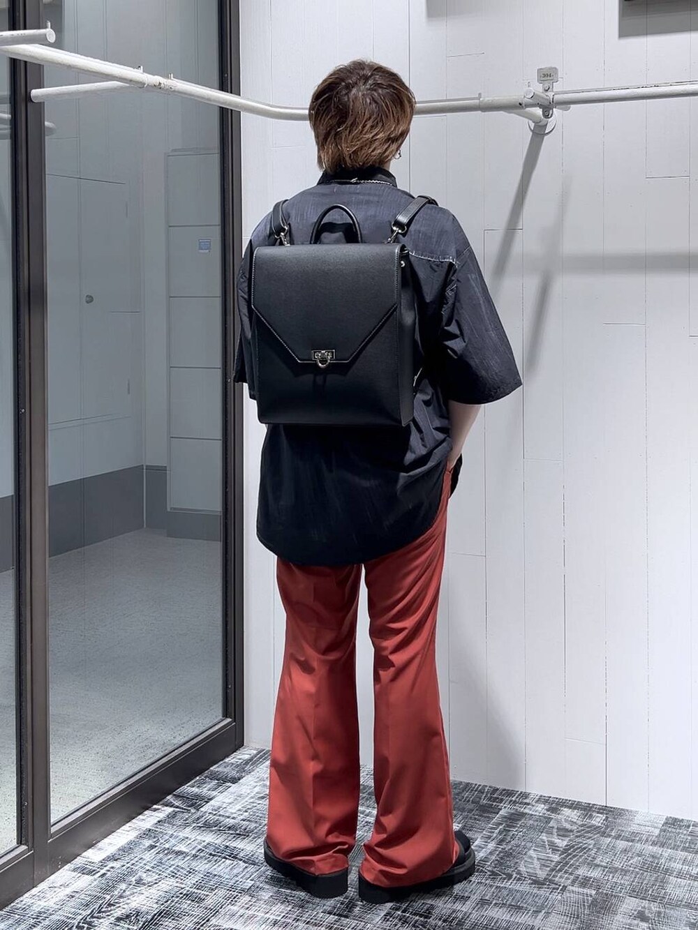 ブラック系のサンダル、ブラック系のショルダーバッグ、オレンジ系のスラックスを着用したメンズの春コーディネートの4枚目の写真