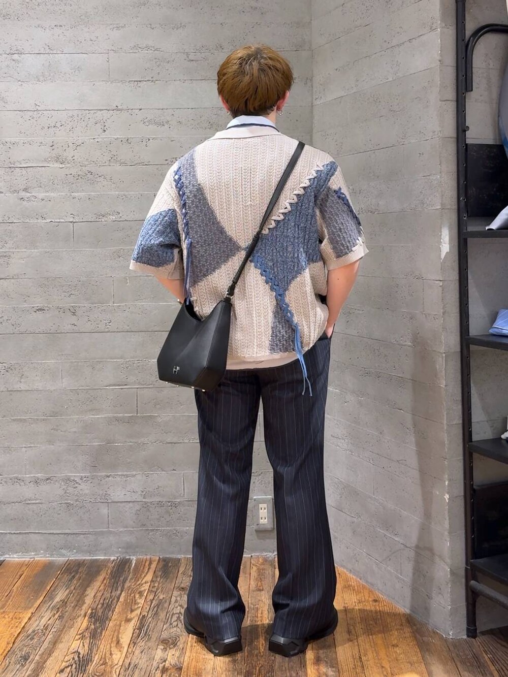 ブルー系のスラックス、ブラック系のドレスシューズ、ブラック系のショルダーバッグを着用したメンズの春コーディネートの4枚目の写真