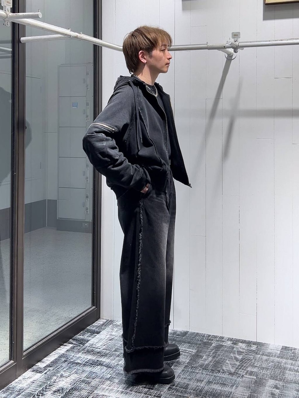 ブラック系のパーカー、ブラック系のブーツ、ブラック系のデニムパンツを着用したメンズの冬コーディネートの2枚目の写真